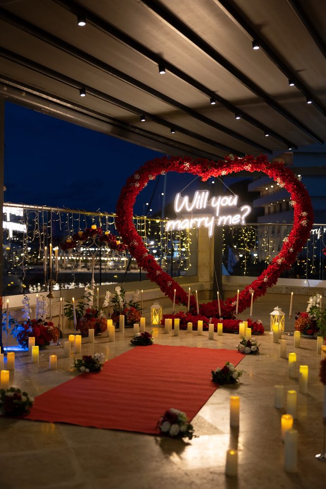 The red rose heart and neon sign lit against the marina at night