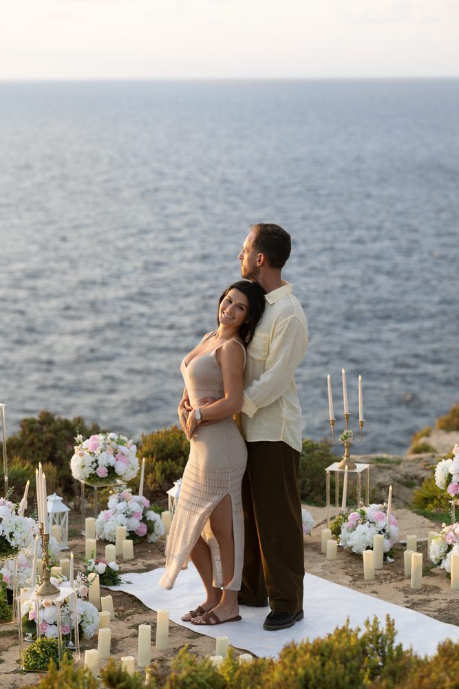 A couple holding each other, looking out over the open sea
