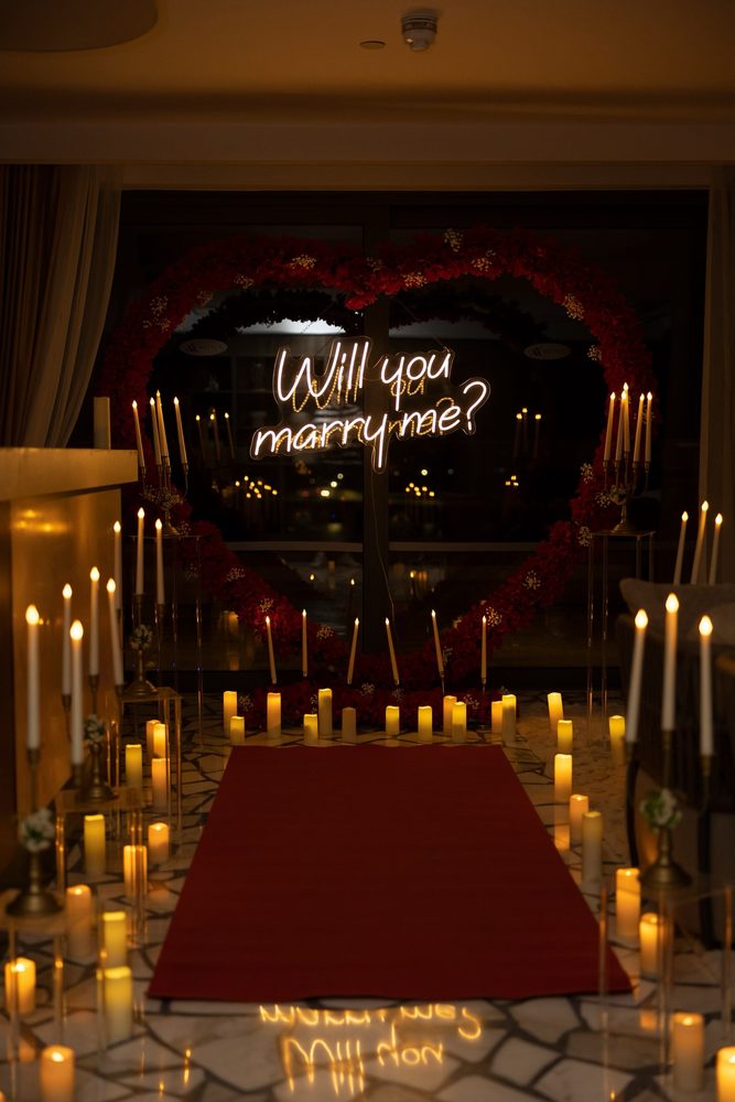 A red carpet leading to the lit neon sign indoors, surrounded by candles